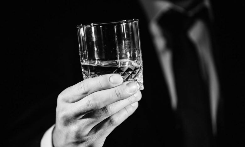 Glass of alcohol in hands of a man