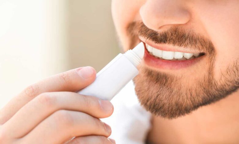 young man using lip balm on his lips
