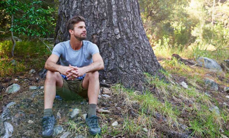 A guy sitting peacefully near a tree