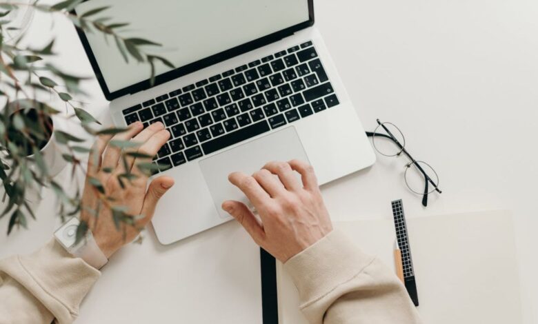 Person in Beige Long Sleeve Shirt Using Macbook Pro