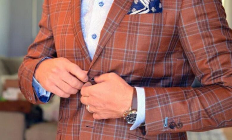 man in plaid suit adjusts buttons