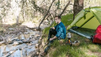 man sitting near a lake and tent
