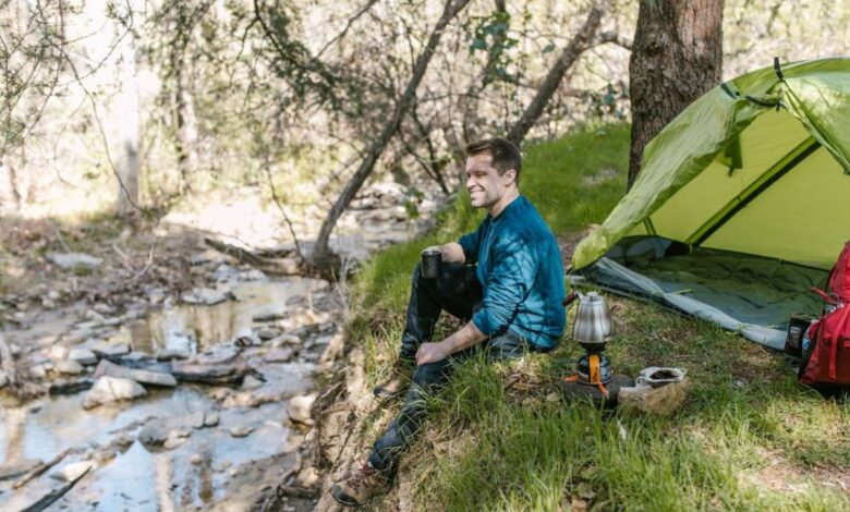 man sitting near a lake and tent