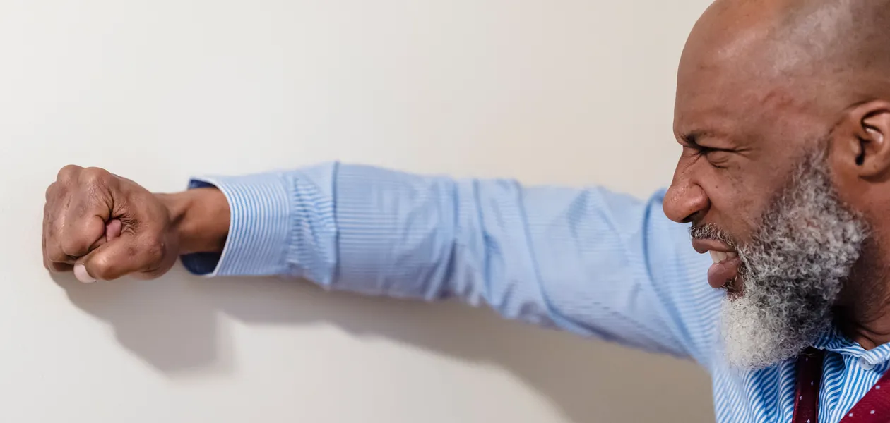 frustrated man punching a wall showing uncontrolled anger