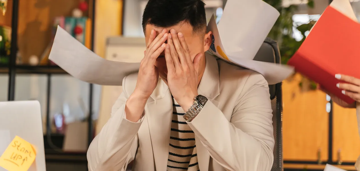 stressed man overwhelmed by paperwork at his desk