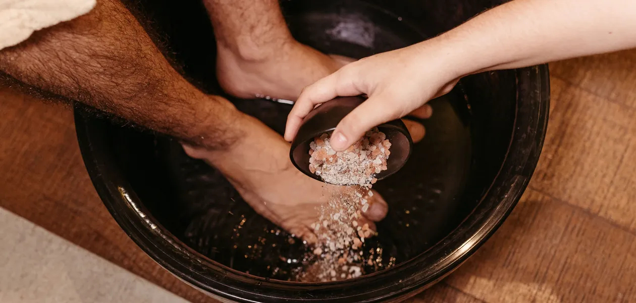 Man soaking his feet in a warm salt water foot bath as a home remedy for athlete's foot