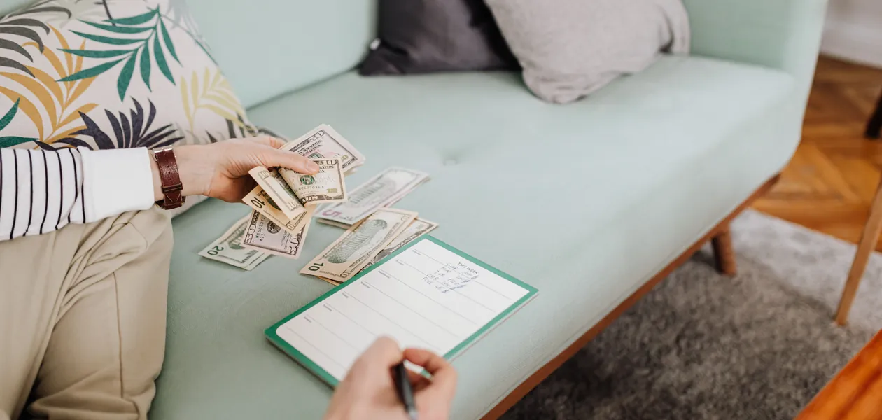 Man counting cash and noting the bachelor party budget in a notebook