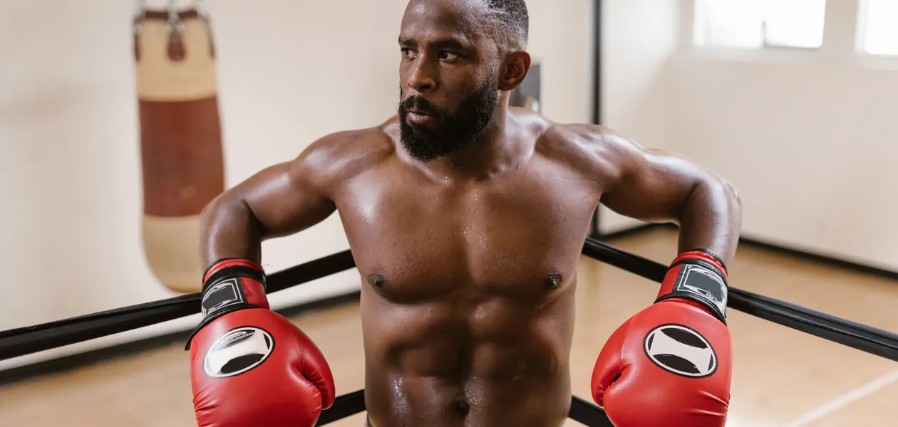 shirtless boxer in gloves showing a lean boxer physique