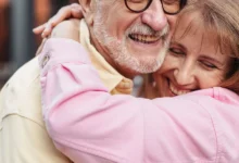 A joyful elderly couple sharing a warm embrace outdoors, exuding love and happiness.