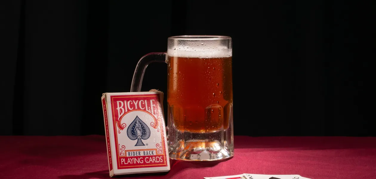 mug of beer beside a spread deck of playing cards
