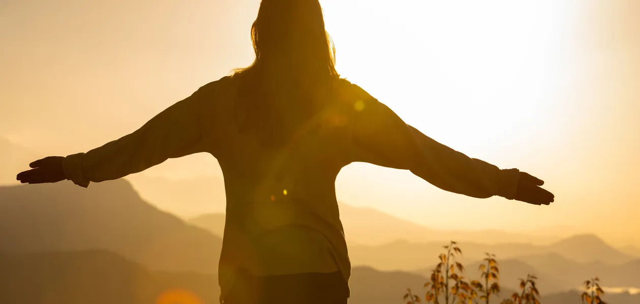 woman with arms open embracing the sunrise as a spiritual awakening
