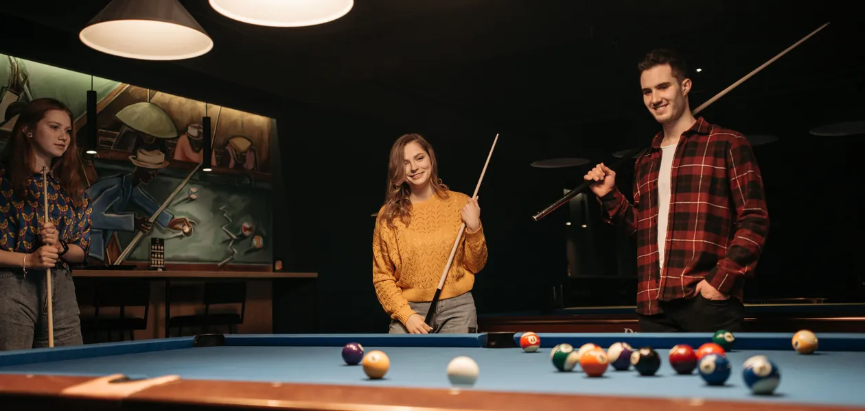 Three friends playing billiards at a pool hall on a night out