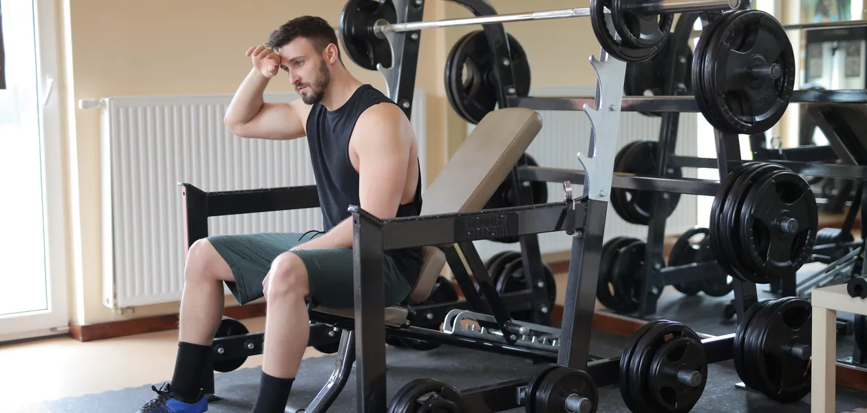 lifter taking a break on a bench beside loaded weights