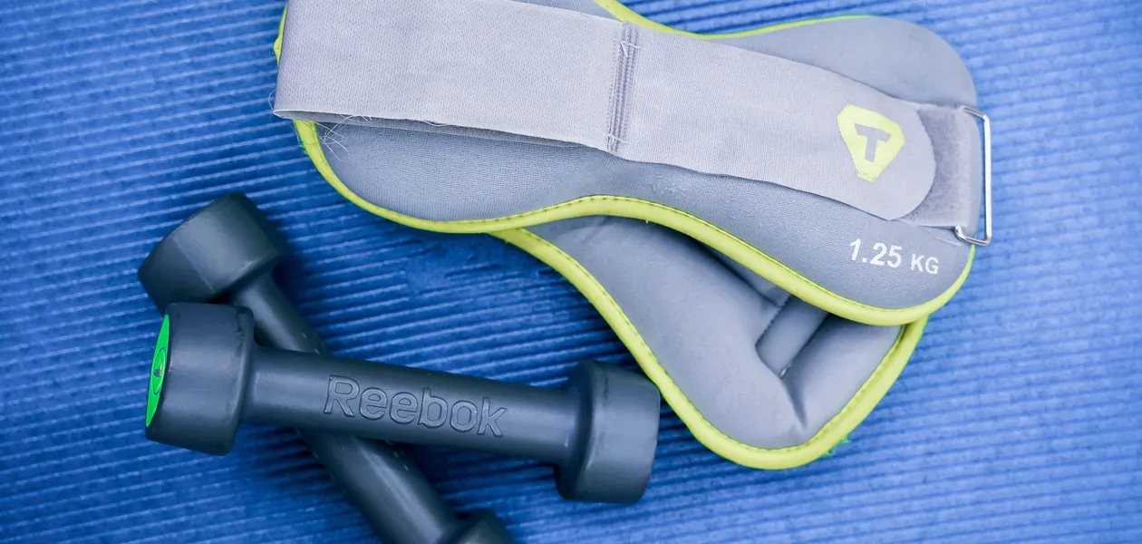 dumbbells and leg weights waiting on a gym mat