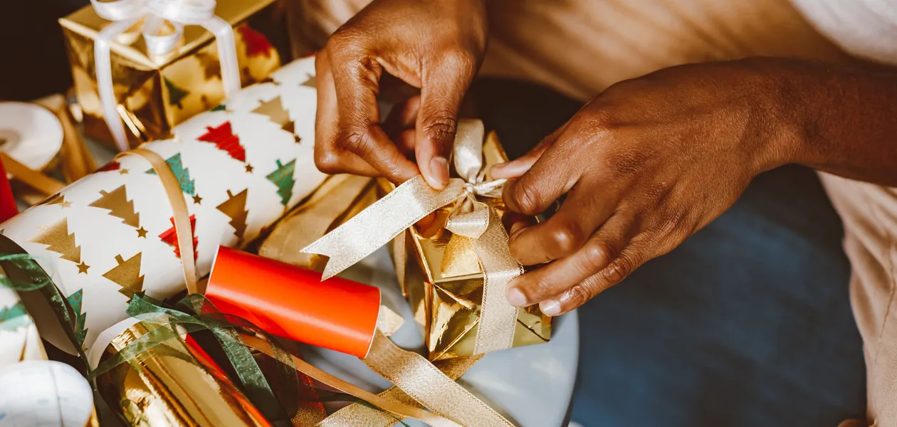 hands wrapping christmas gifts with ribbon