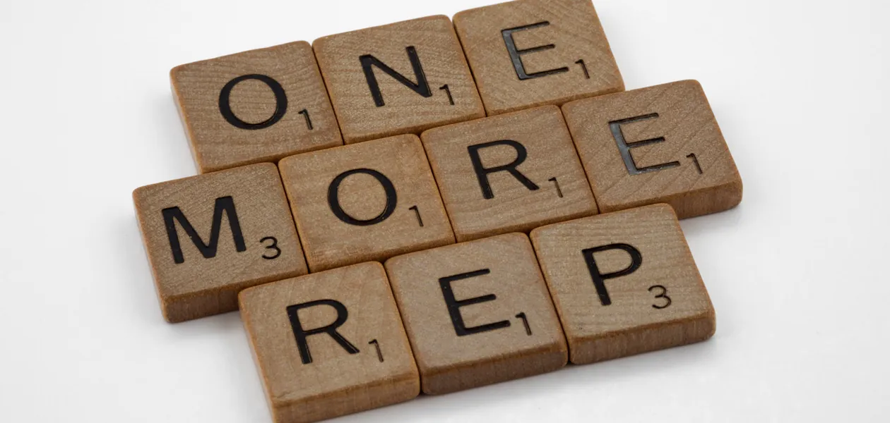Scrabble tiles arranged to spell 'One More Rep', symbolizing fitness motivation.