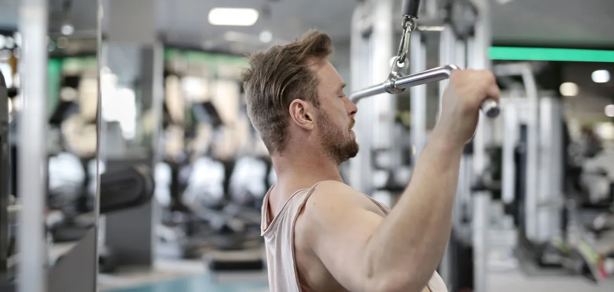 Focused man performing lat pulldown exercise indoors.