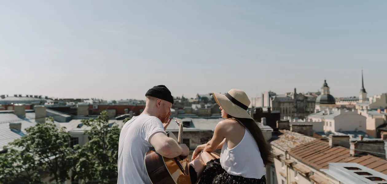 couple playing acoustic guitar together on a rooftop
