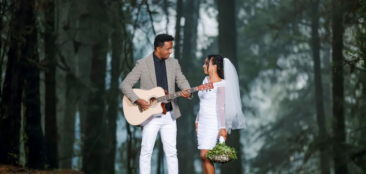 groom playing guitar for his bride in a forest