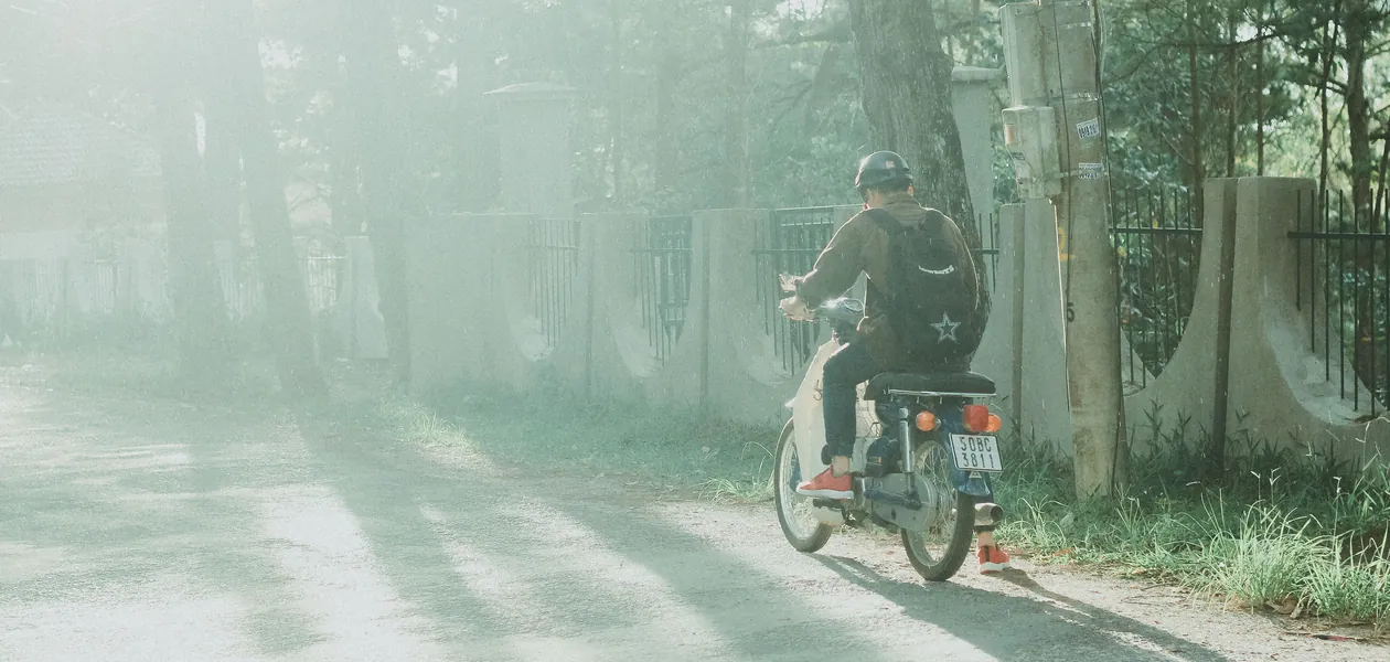 motorcycle rider on a sun-dappled country road