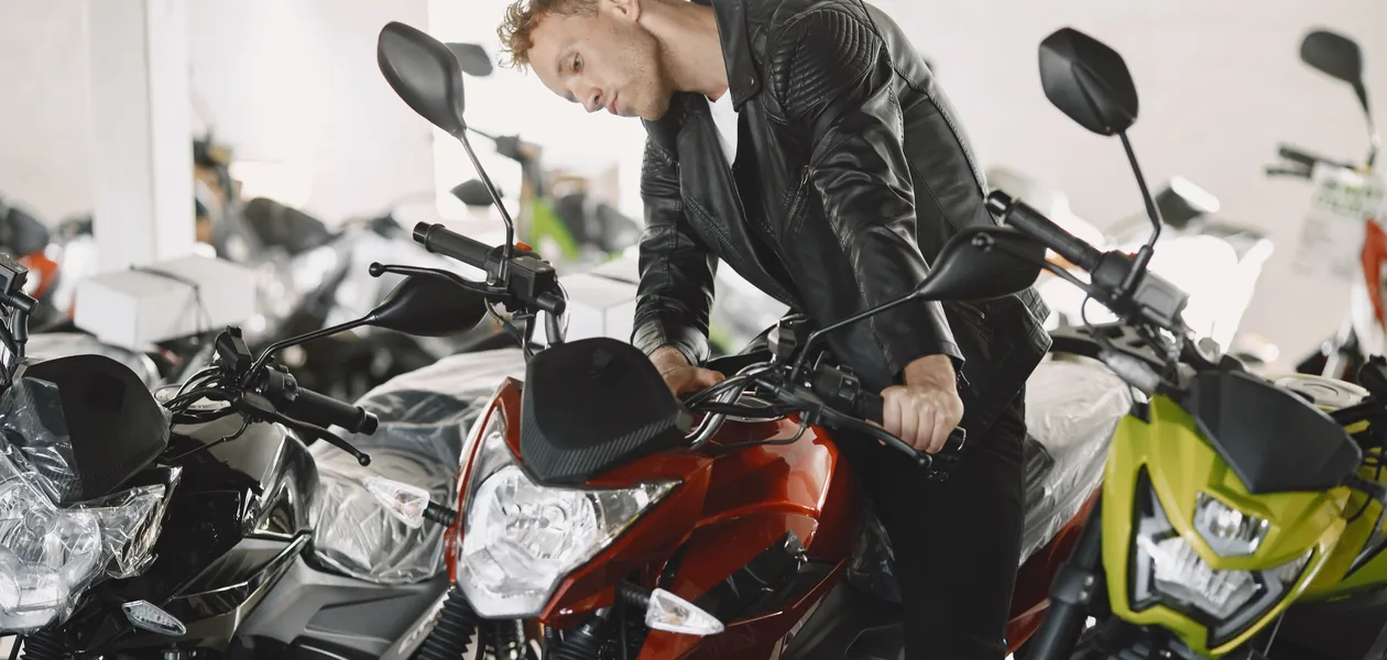 man in a leather jacket inspecting motorcycles before buying
