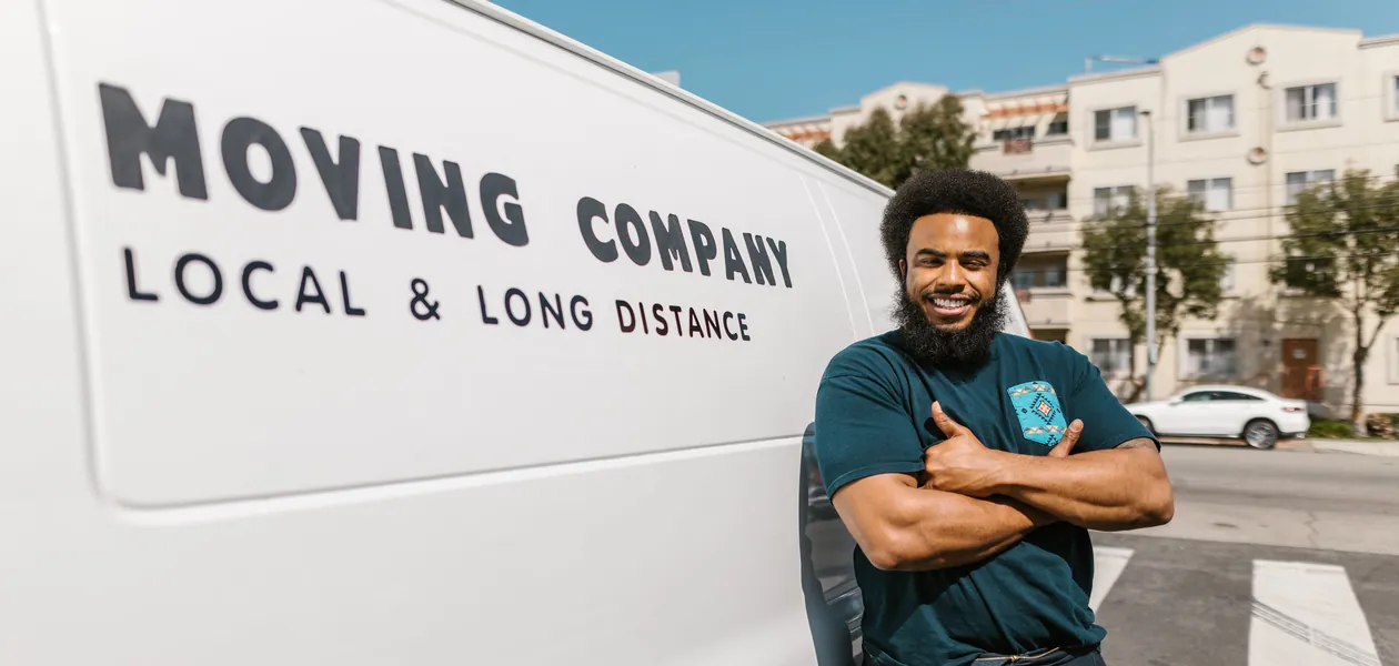 Professional long-distance mover standing beside a moving company van