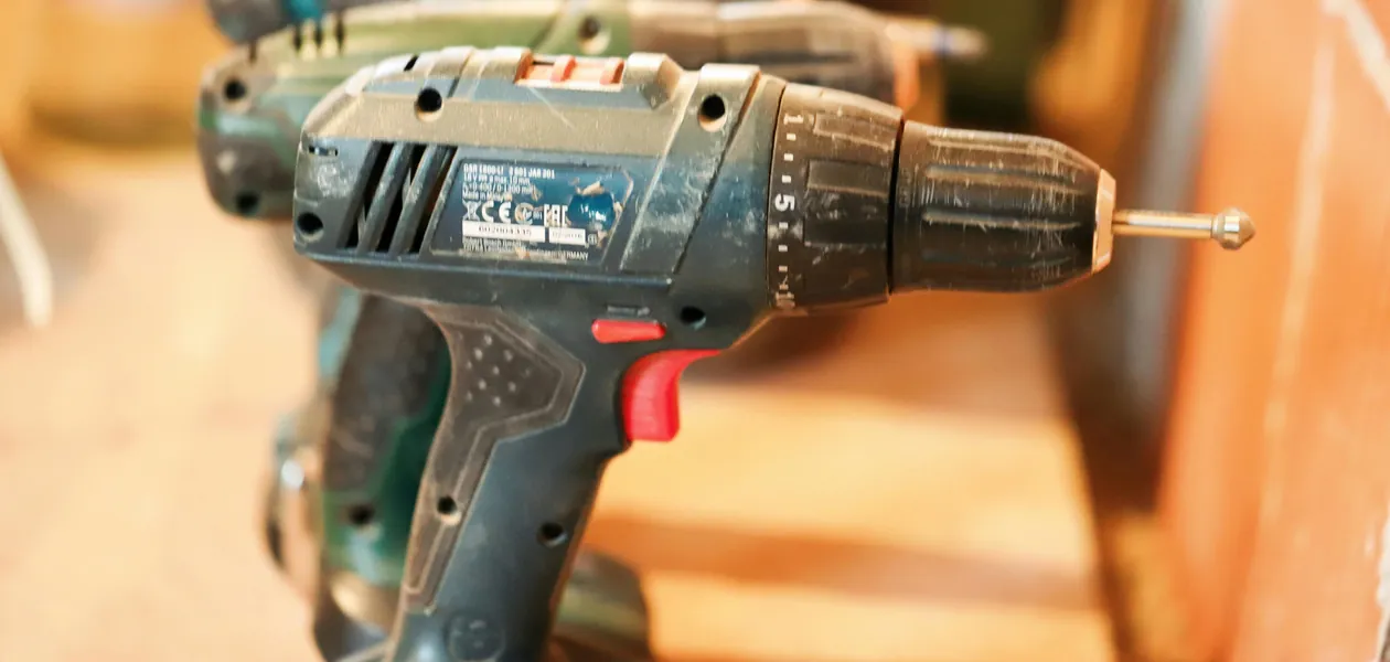 row of cordless power drills lined up on a wooden workbench