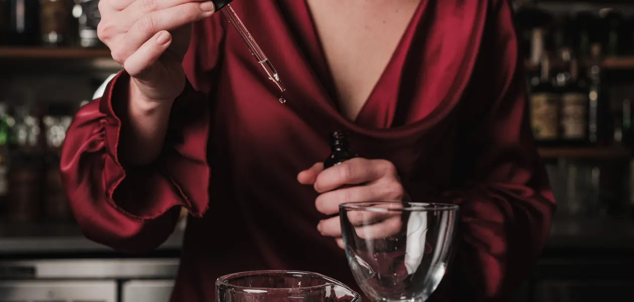 bartender adding non-alcoholic bitters to a cocktail
