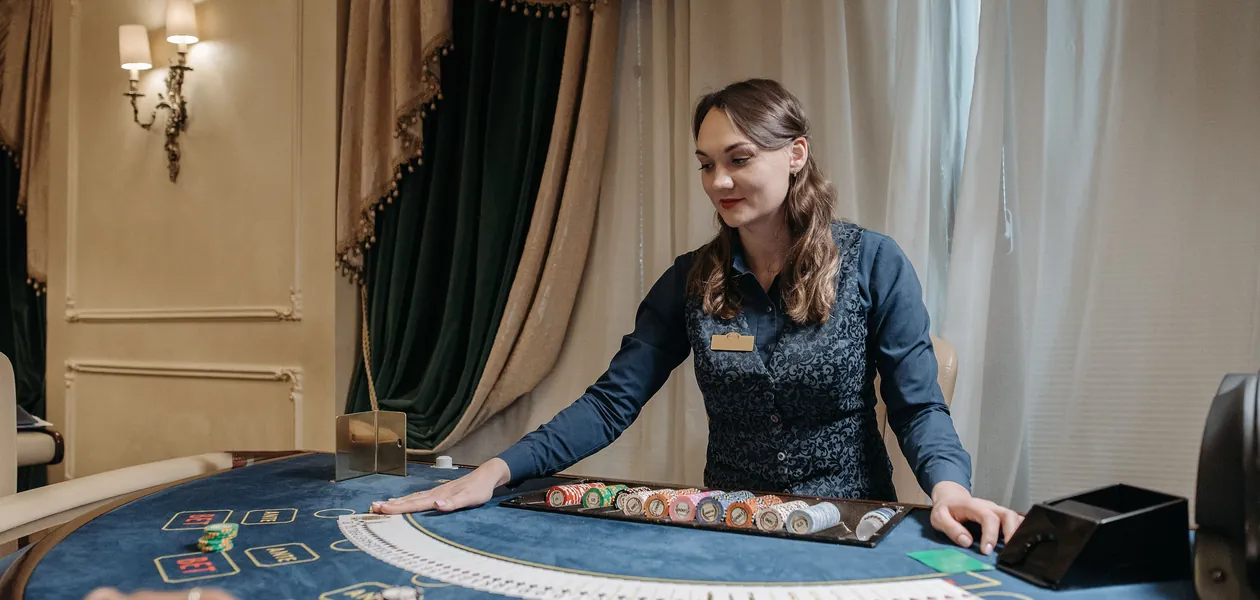 casino dealer holding cards at a poker table