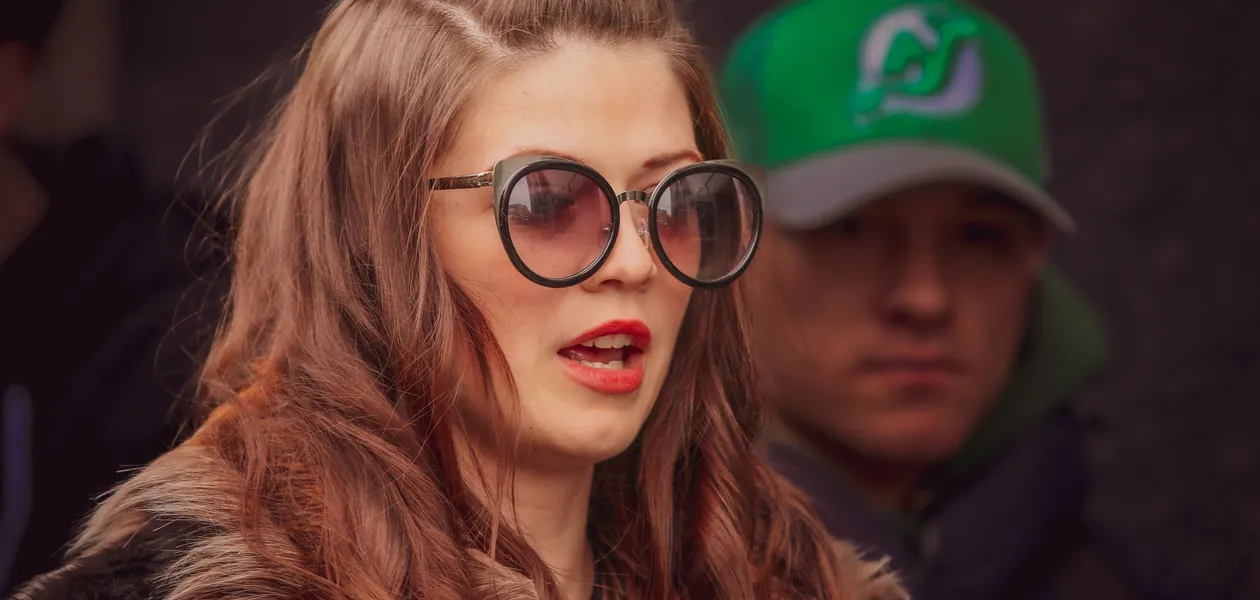 Fashionable woman with sunglasses and red lipstick at an outdoor event in NYC.