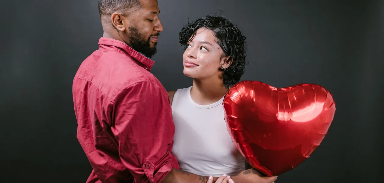 A loving couple embracing with a red heart balloon, perfect for Valentine's Day themes.