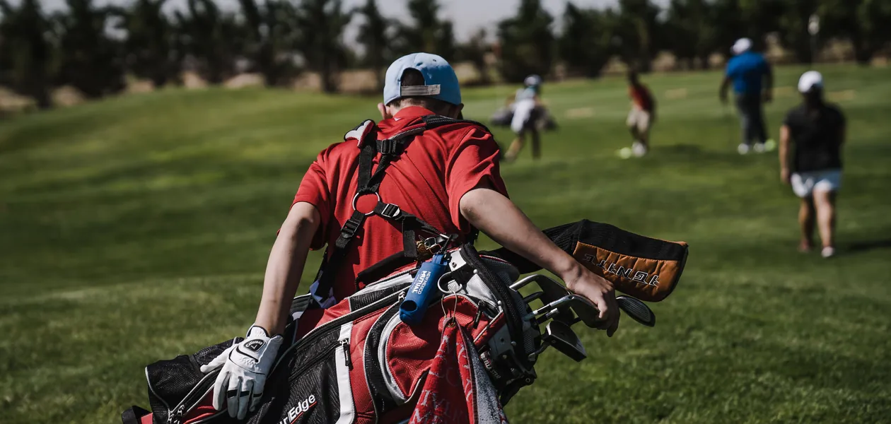 Golfer carrying his bag down the fairway on a green course