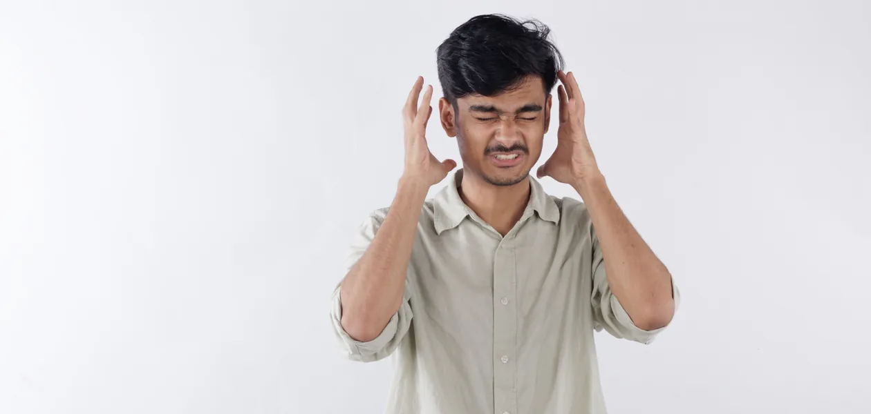 Young man expressing frustration, hands on head, isolated background.